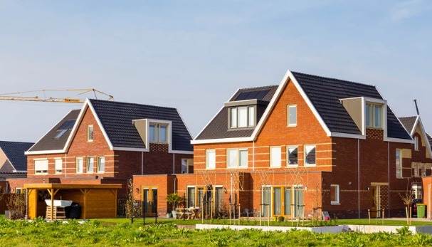 Rode bakstenen huizen met daken en garage.